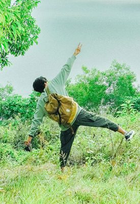 A person with arms and legs outstretched seen from behind looking joyful in nature