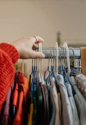 hands selecting second hand clothes on a clothes rail
