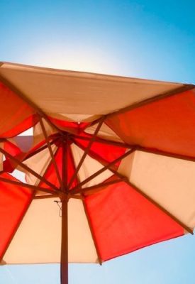 a red and white sunshade with bright sunlight behind