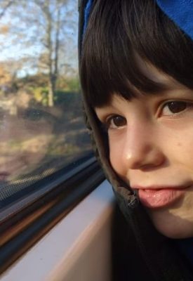 A child smiles looking out of a train window