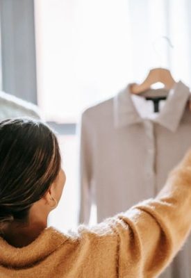 a woman holding up clothes on a clothes hanger seen from behind
