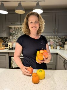 Emma Taylor holding fresh fruit and vegetables in her kitchen