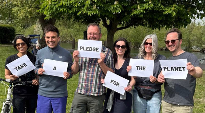 A group of local people hold up signs saying 'pledge for the planet'